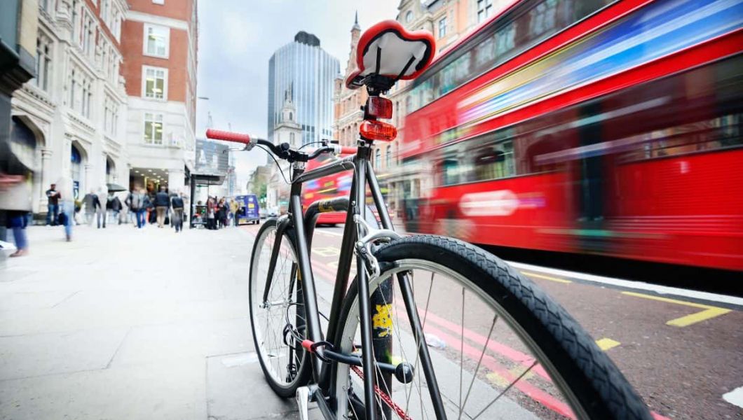 a bike and red bus on a main street in london