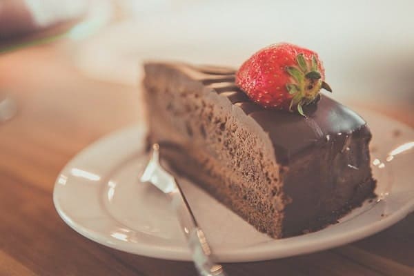 Slice of chocolate cake with a strawberry on top.