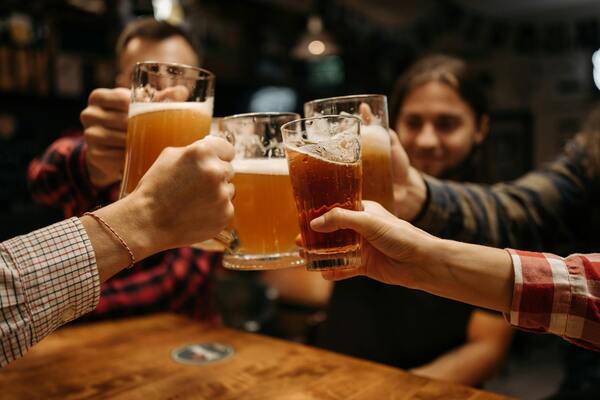 people clinking beer glasses at a pub table