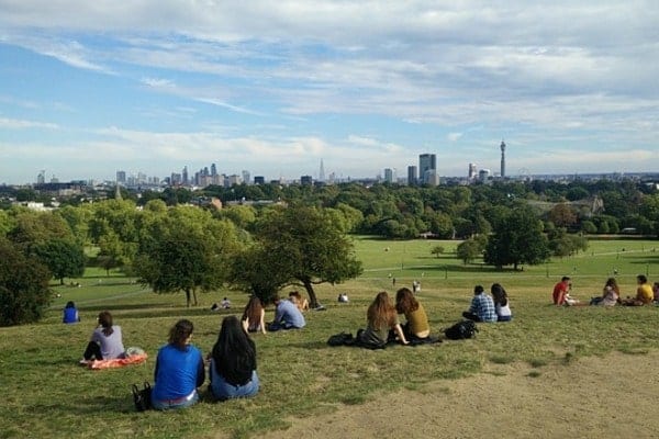 People sitting on Primrose Hill London, watching the skyline.