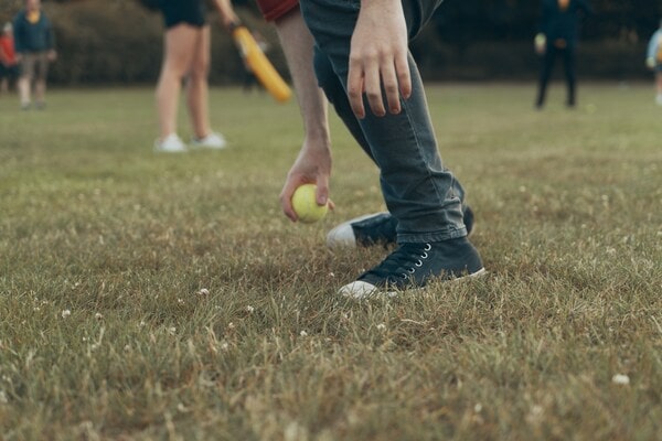 People playing rounders, with one person kneeling down holding the ball