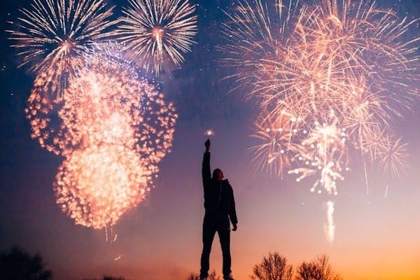 A man holding a light and watching fireworks