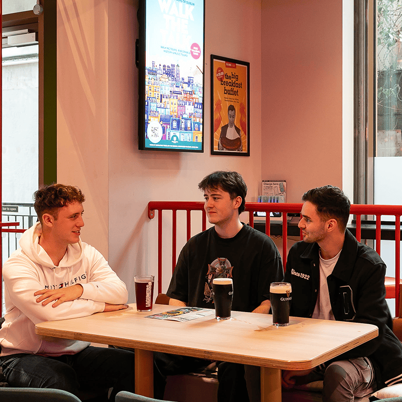 Three guests enjoying a drink at the hostel bar