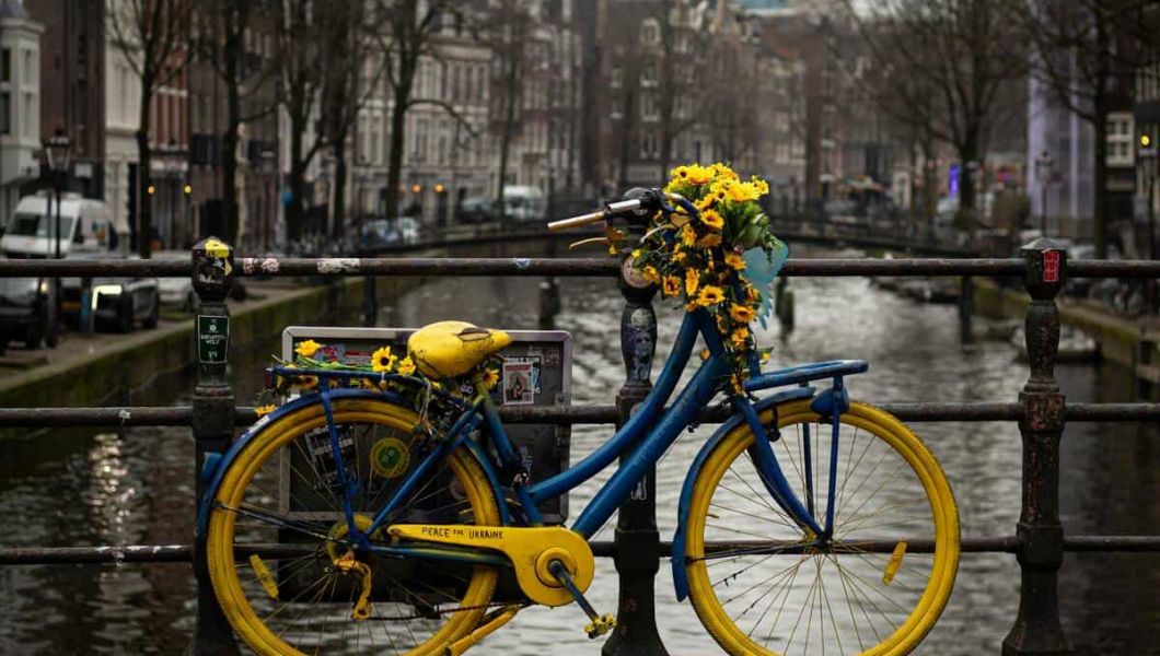 yellow and blue bike in front of a canal in Amsterdam