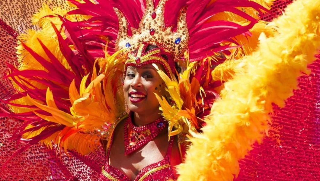Woman in red and yellow feather costume at the Notting Hill Carnival