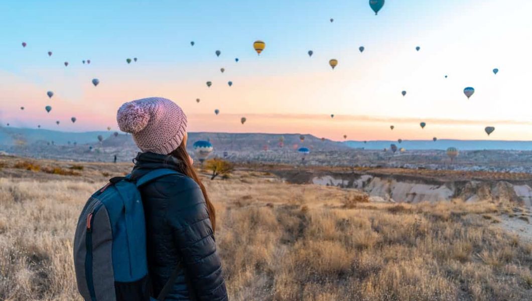 Woman with a backpack watching hot air balloons in the sky